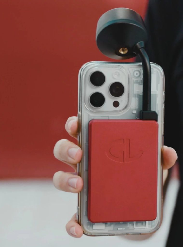 Hand holding a phone with the red General Laser GLRM receiver and black antenna mounted on its back.